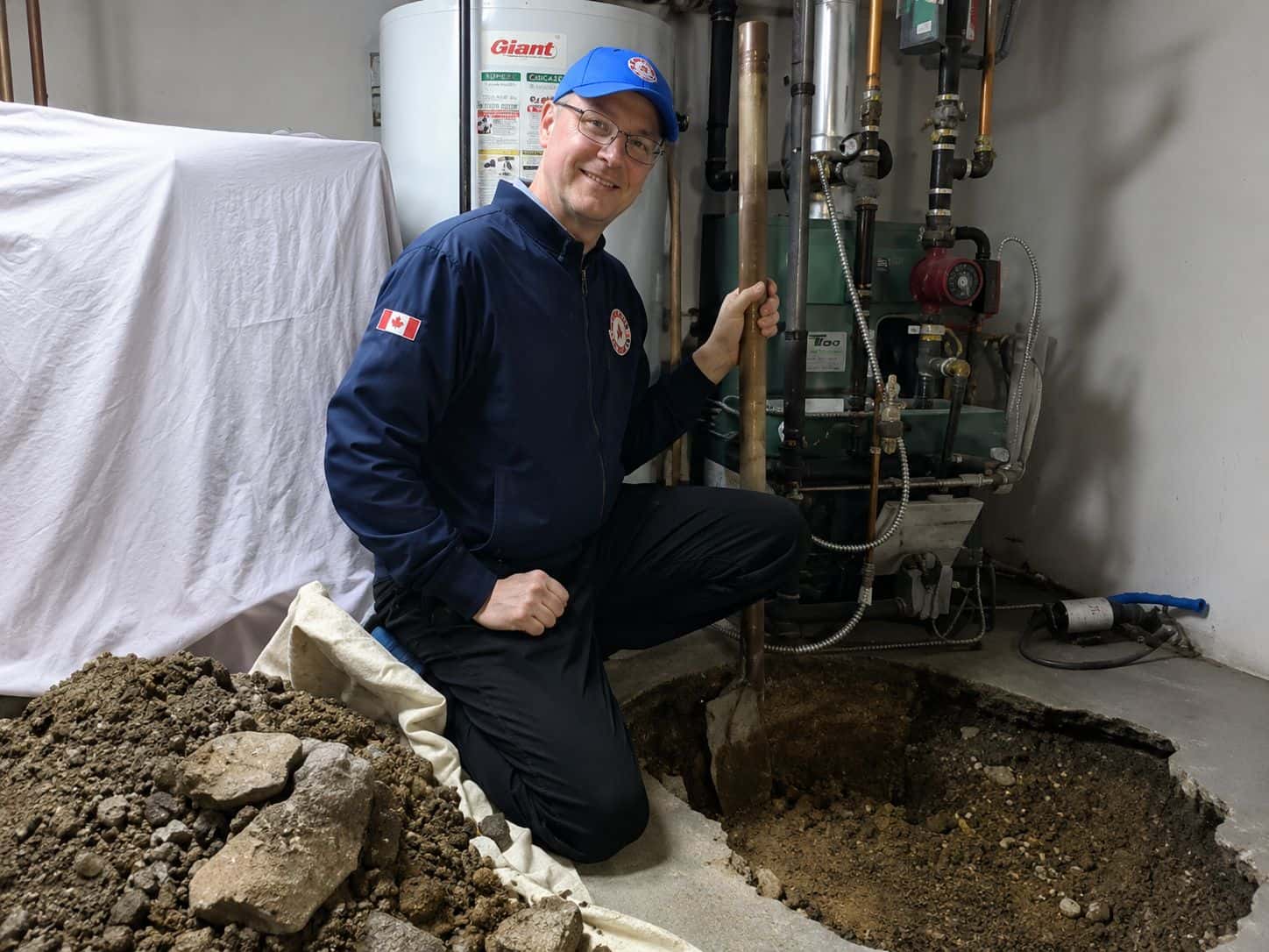 Basement floor opened up for drain work, with the Waterworks plumber on site