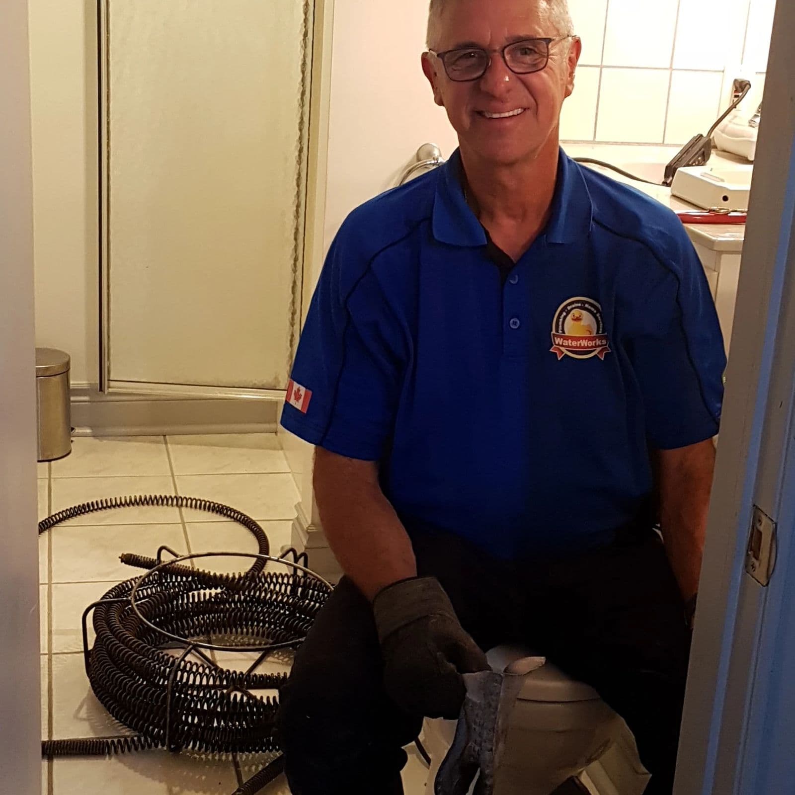 Michael from Waterworks kneeling beside a drain cable machine in a basement