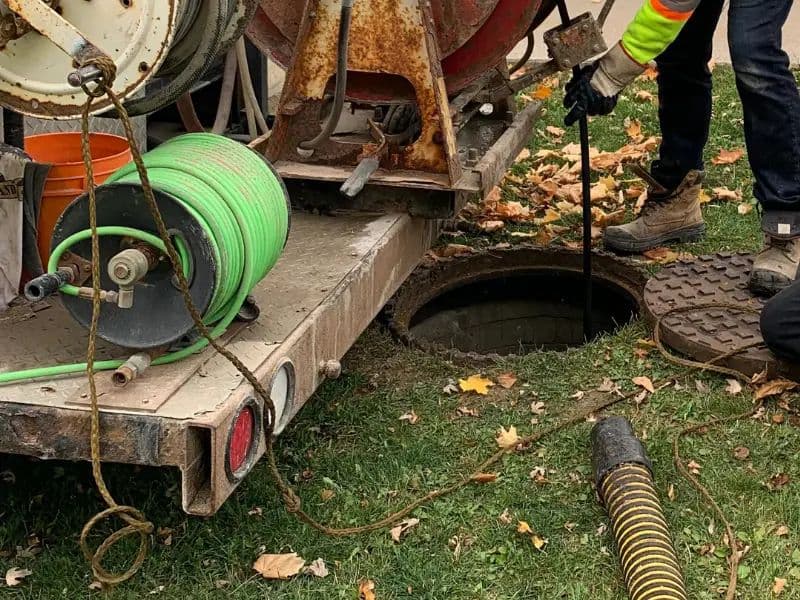 Sewer cleaning machine on a trailer beside an open manhole