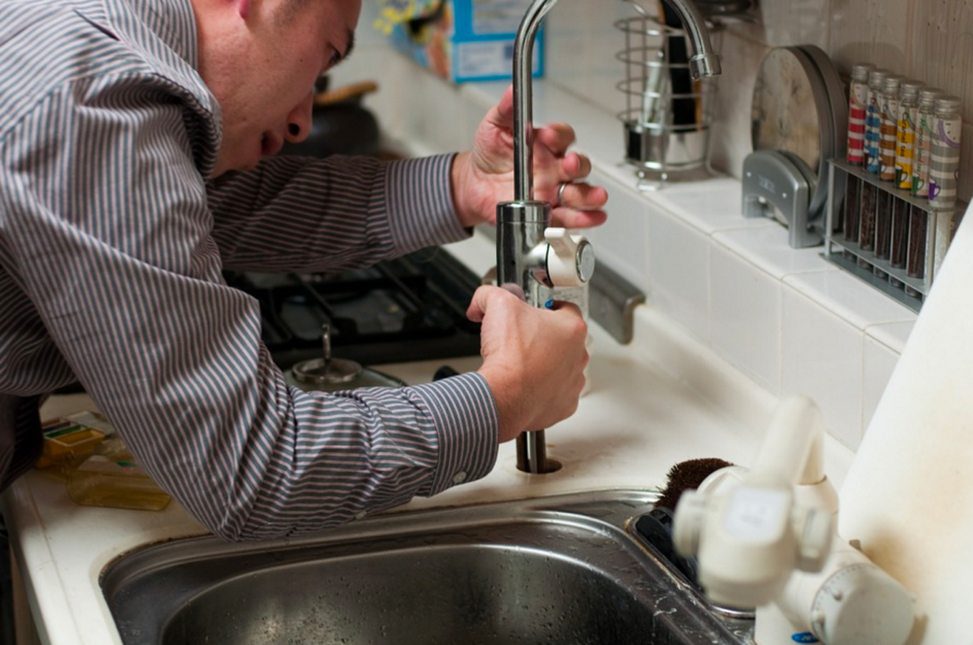 a DIY plumber attempting to install a faucet into a kitchen countertop