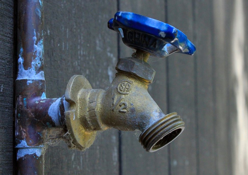 Large outdoor tap with plumbing issues on the pipes.